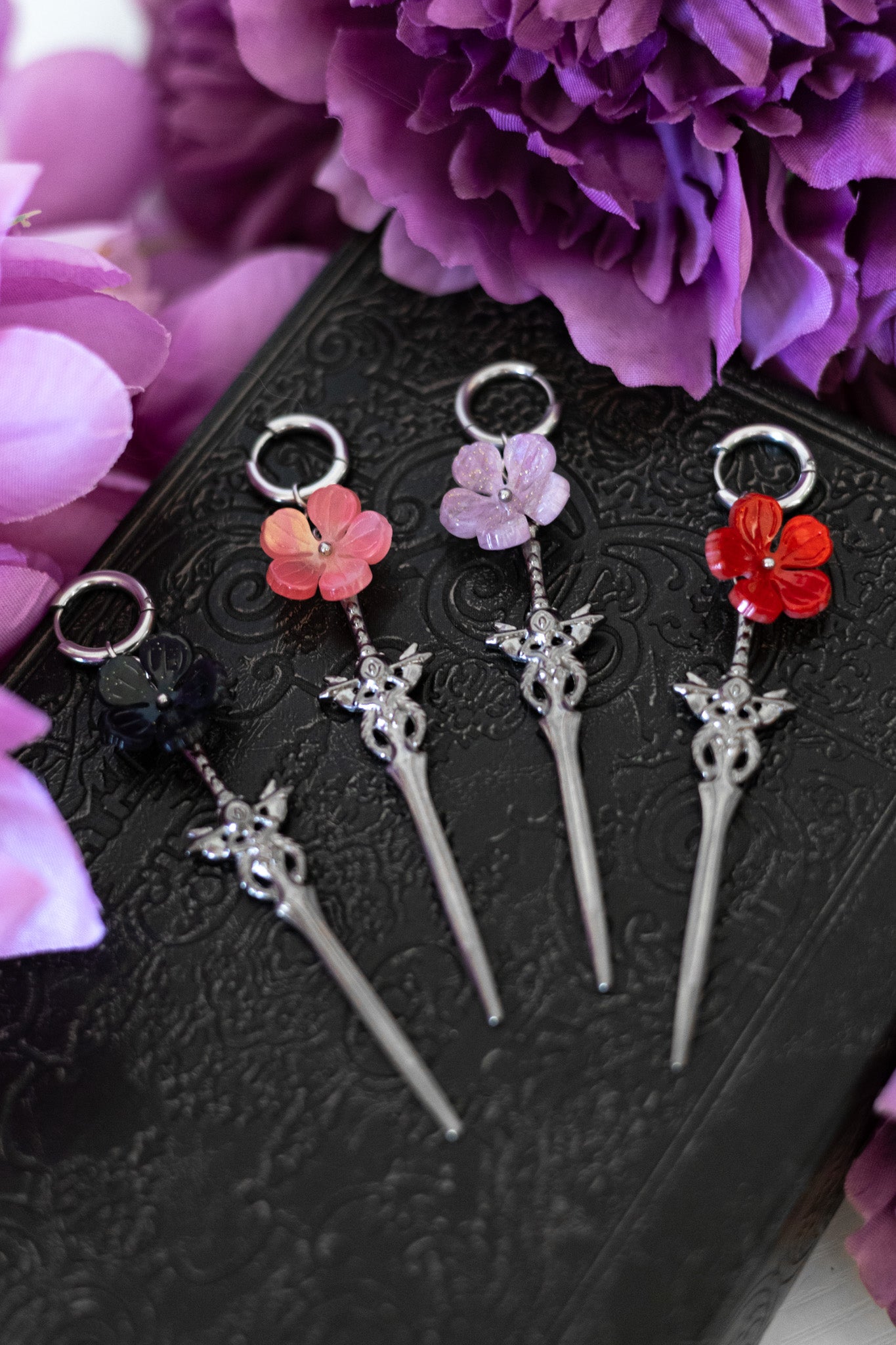 Set of decorative hair pins with floral and sword designs on a black background with purple flowers.