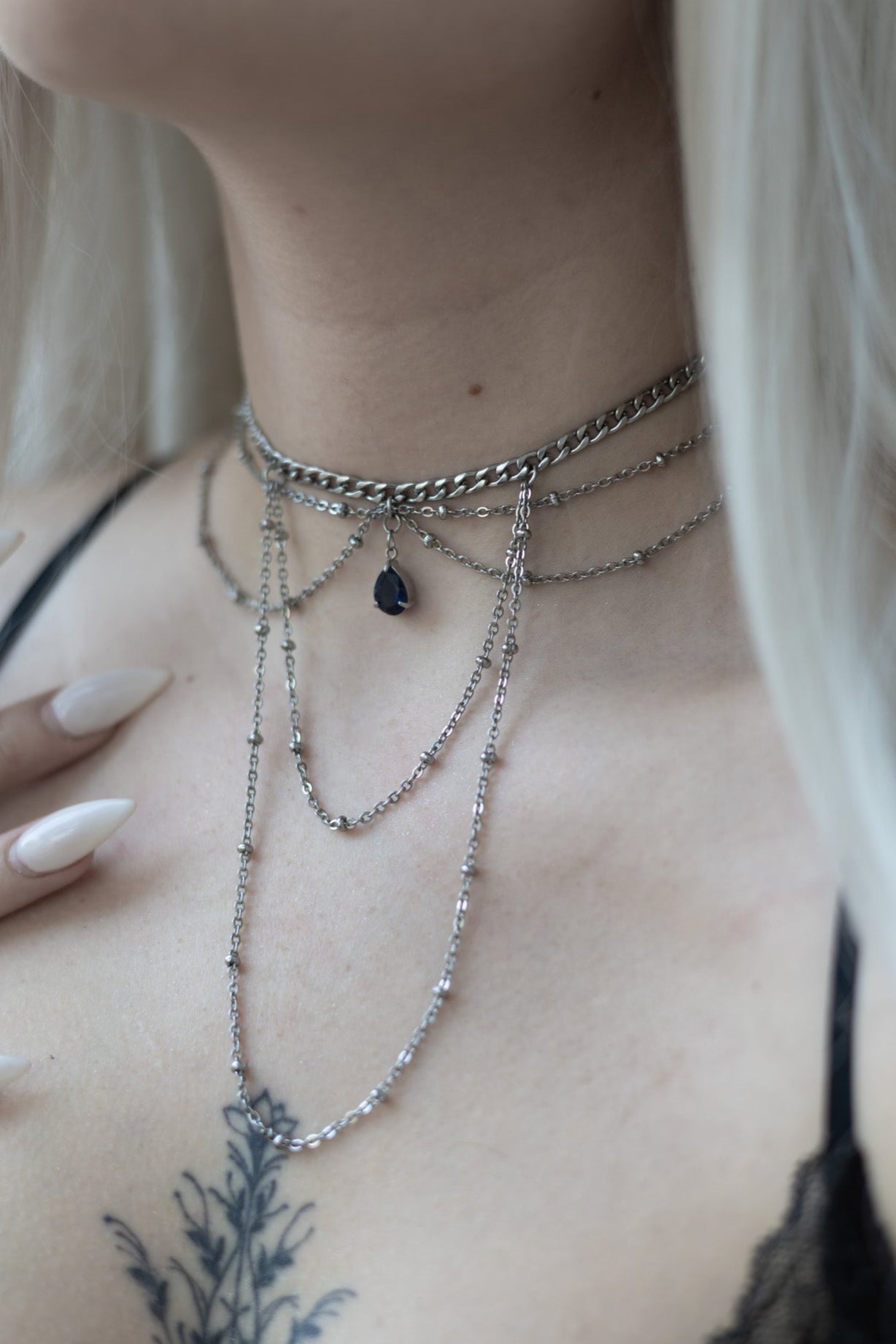 A layered choker necklace with a jewel at the neckline, worn by a person with blonde hair.